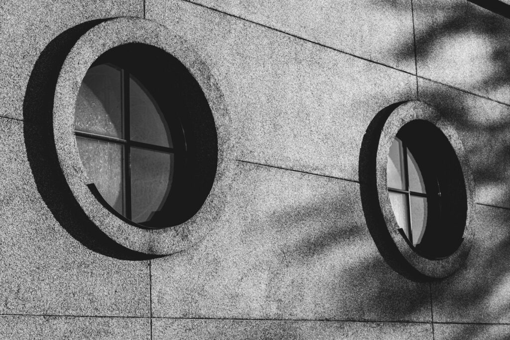 Grayscale of round modern windows on a stone building